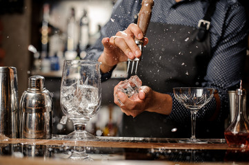 Bartender splitting a piece of ice at a bar counter