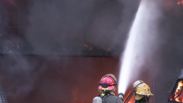 Flames burn as brave firefighters work on a dangerous house and car on fire. ProRes file, shot in 4K UHD.