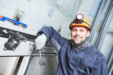 smiling machinist with spanner adjusting lift in elevator shaft © Kadmy