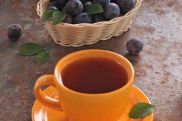 A cup of tea and plum on the table