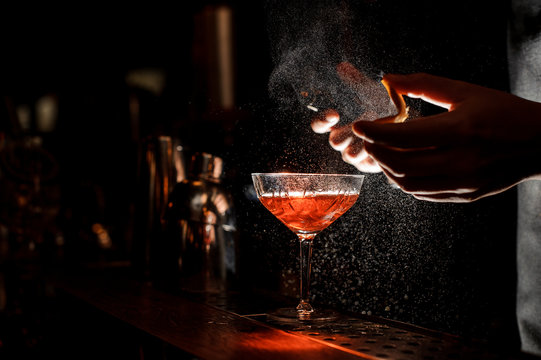 Naklejka Bartender sprays an orange peel in cocktail glass