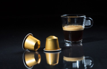 Fototapeta na wymiar Espresso capsules and coffee cup on black background, Closeup view with details