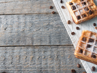 Soft Viennese Belgian waffles with powdered sugar and coffee beans on rustic wooden background Copy space