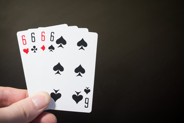 Abstract: man hand holding playing card four six isolated on black background with copyspace poker set four six