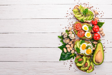 Fototapeta na wymiar A set of avocado sandwiches, cherry tomatoes and quail eggs and chia seeds. On a wooden background. Top view. Free space for your text.