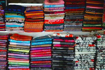 Naklejka premium beautiful and colourful silk and cotton Indian scarfs sold in souvenir shop market stall