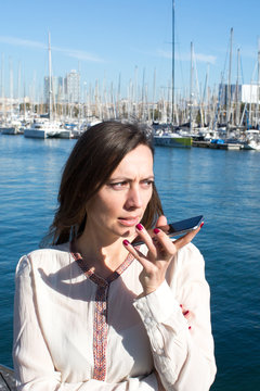 Frau spricht eine Sprachnachricht aufs Telefon im Hafen