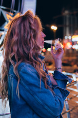 young beautiful blonde girl standing on a night street with a cigarette, smokes