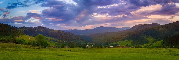 Carpathian mountains summer landscape with cloudy colorful sky and village at sunset, natural travel background