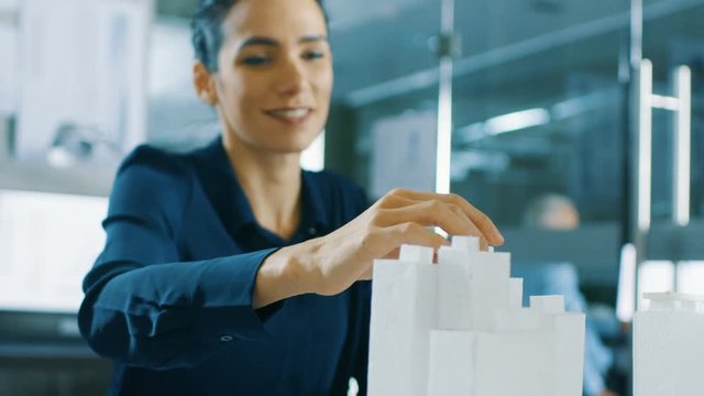 Female Architectural Designer Adds Component to a Building Model, She Works on a City District Urban Planning Project. Beautiful Woman in Stylish Office. Shot on RED EPIC-W 8K Helium Cinema Camera.