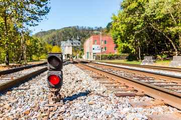 Red traffic light for train with metal iron railroad tracks in Thurmond, West Virginia with nobody...