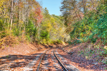Railroad tracks in autumn fall in West Virginia with golden foliage, fallen leaves and road curve