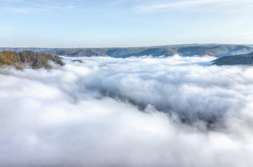 Fototapeta na wymiar Mountains and fog, mist clouds in morning floating above forest trees, covering, blanketing valley in Grandview Overlook, West Virginia