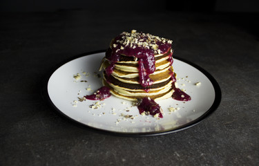 pancakes with jam and nuts on a dark background