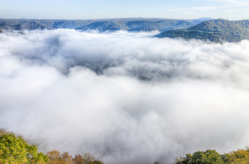 Mountains and fog, mist clouds in morning floating above forest trees, covering, blanketing valley in Grandview Overlook, West Virginia