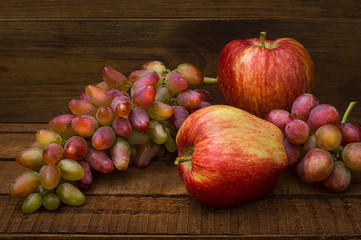 Fototapeta na wymiar Apples and grapes on a wooden rustic background. Still life for thanksgiving with autumn fruits. Selective focus. Top view