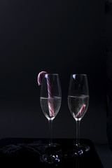 two glasses of champagne with candies on a black background