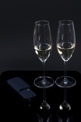 Black device and 2 glasses with champagne on a black background
