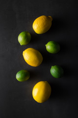 Limes and lemons on a dark background.