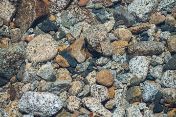Stones in river of different shape and colors, closeup.