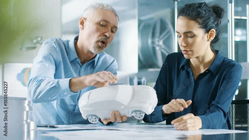 Poster experienced automotive designer and female engineer works with a concept car prototype model, perfec