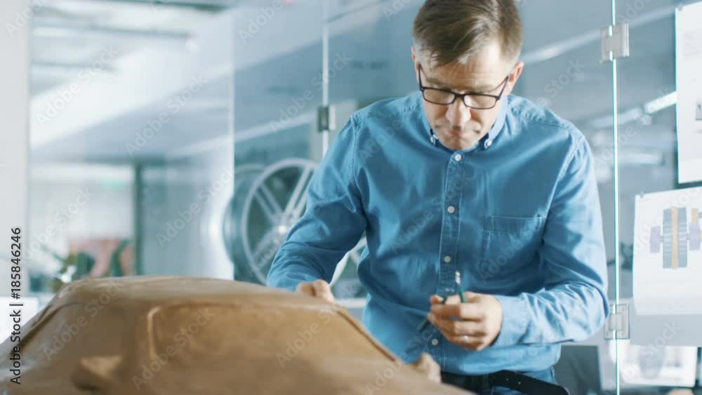 Poster experience automotive designer with a rake sculpts prototype car model from plasticine clay. he work