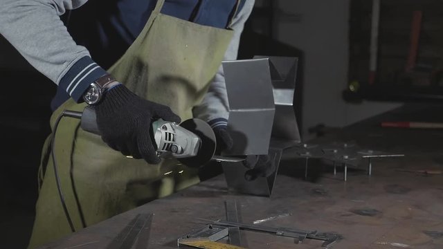 Craftsman using an angle grinder for polish metal detail at workshop.
