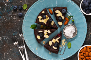 Chocolate brownie with blueberries and cherries on a blue plate.