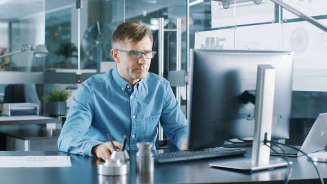 Experienced Industrial Engineer Working on Personal Computer in the Stylish, Modern, Glass Office. Shot on RED EPIC-W 8K Helium Cinema Camera.