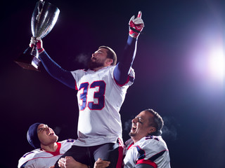 american football team with trophy celebrating victory