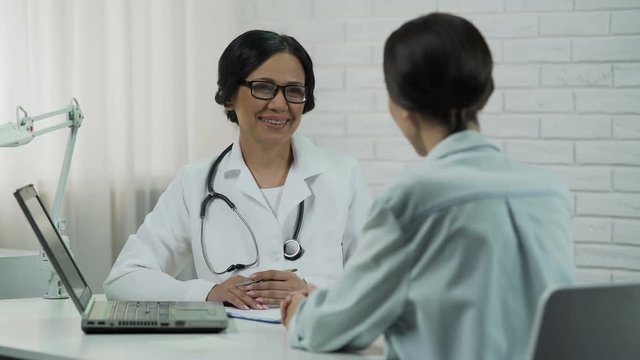 Doctor showing test results on laptop, effective treatment, patient recovering