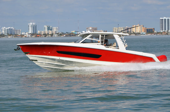 Well appointed sports fishing boat, red with white trim,cruising on the florida intra-coastal waterway off Miami Beach.