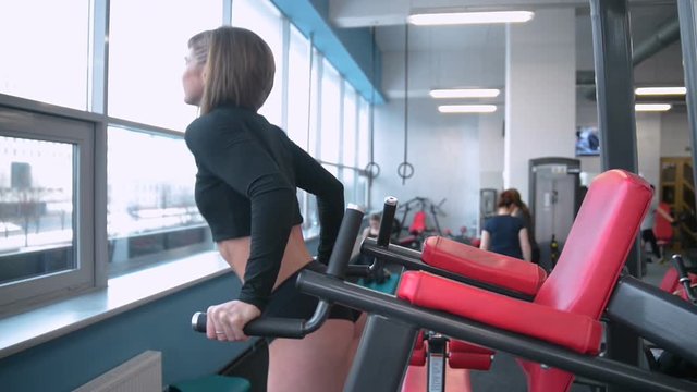 Beautiful sexy athletic young Caucasian girl working out training arms abs legs butt, ass in the gym gaining weight pumping up muscles bicep with dumbbells and on machines gaining weight and poses