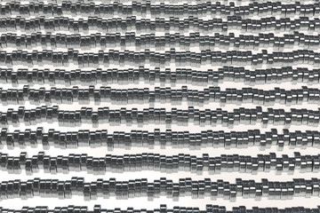 Pattern of brushed metal cylinder tablets on white background