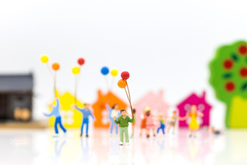 Miniature people: children hold balloons, and play together, using as background International day of families concept.