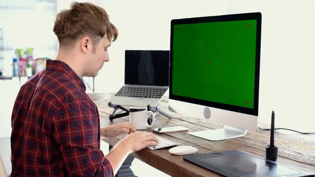 Young caucasian male freelance typing on keyboard and looking at mock up display