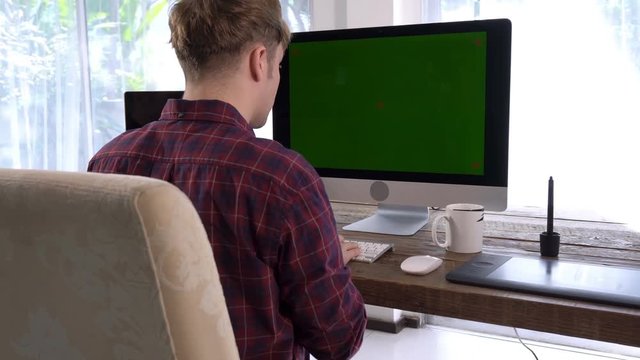 Behide of freelancer programmer male typing on wireless keyboard