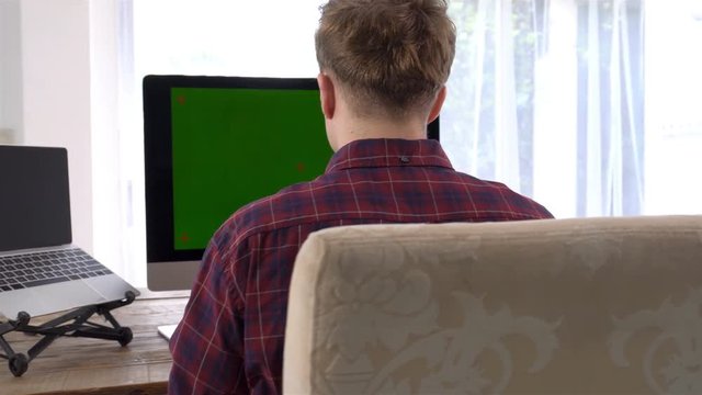 A caucasian male typing on a wireless keyboard on the wooden table