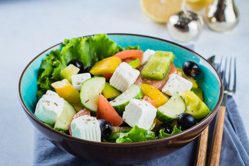 Traditional Greek salad with fresh vegetables, feta cheese and black olives on blue stone table background. Healthy Food Snack Concept. Close up