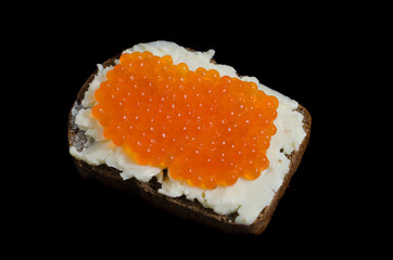 Red caviar and butter smeared on a piece of black bread