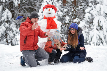 Fototapeta na wymiar winter fun. a girl, a man and a boy making a snowman.
