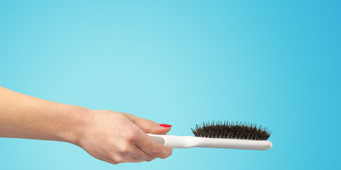 Woman hand with a hair comb isolated on a color background