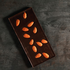 The dark chocolate with almonds on a textured steel background