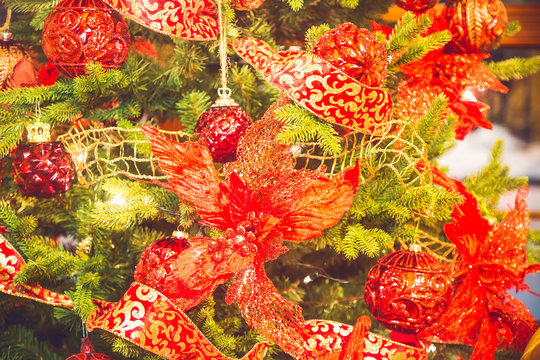 Celebration of New Year and Christmas background. Details of a Christmas tree. Detail shot of Christmas tree branches with Christmas toys and red ribbons.