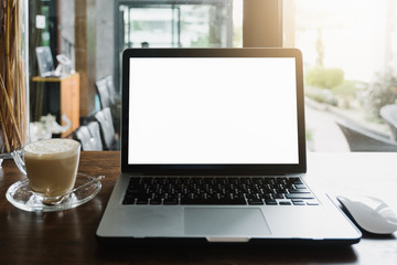 Mockup image of business woman using and typing on laptop with blank white screen and coffee cup on glass table in modern loft cafe, Soft focus on vintage wooden table.