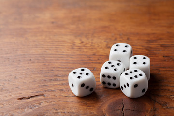 Game of chance concept. Gambling devices. White dice on rustic wooden board. Copy space for text.