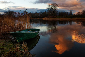 standing beside the river among the reeds at night, a lone boat