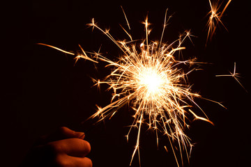 Fototapeta premium Blank background with bengal fire .Sparkler . New year party sparkler on black background A man holds a burning Bengal flame in his hands