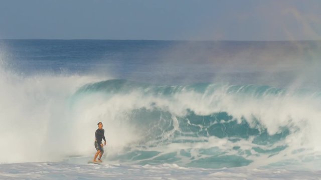 a surfer performs a bottom turn, stalls and is covered up by a wave at pipeline on the north shore of oahu