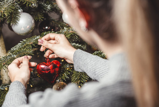 Frau h&auml;ngt herzf&ouml;rmige Christbaumkugel auf
